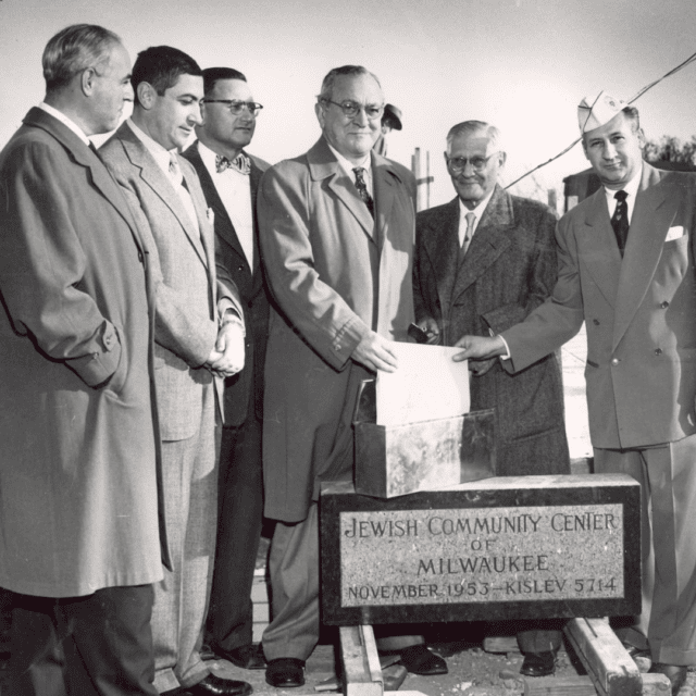 A group of men standing next to a plaque.