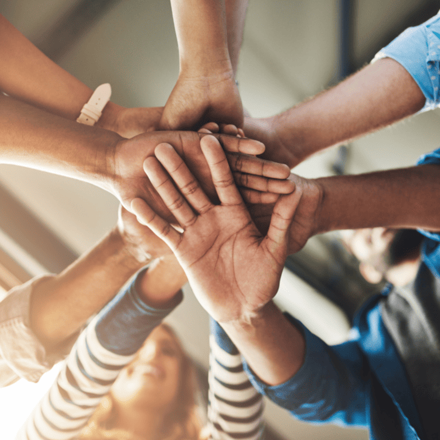 A group of people putting their hands together in a circle.