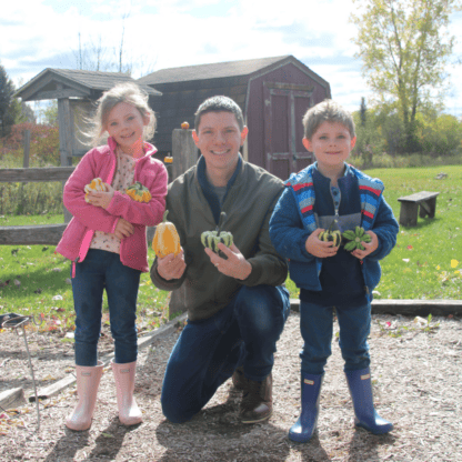 A man and two children holding pumpkins.