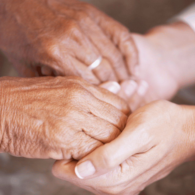 A group of elderly hands holding each other.
