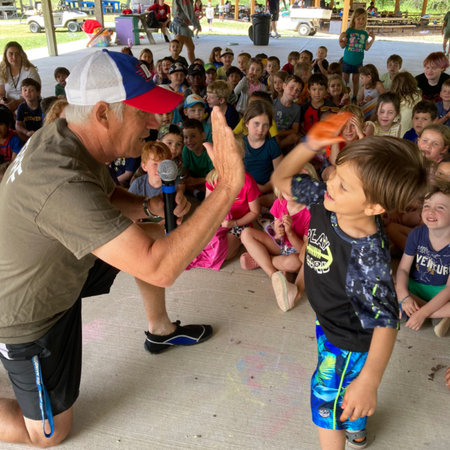 A man is giving a high five to a group of children.