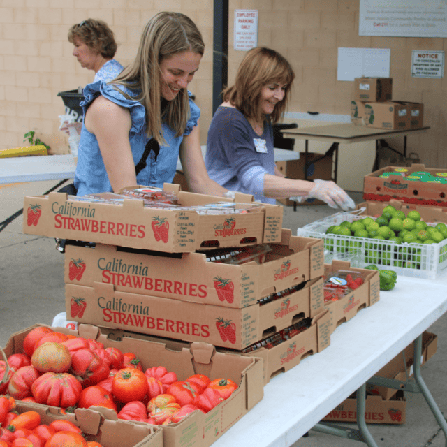 A woman standing next to a box of fruit.