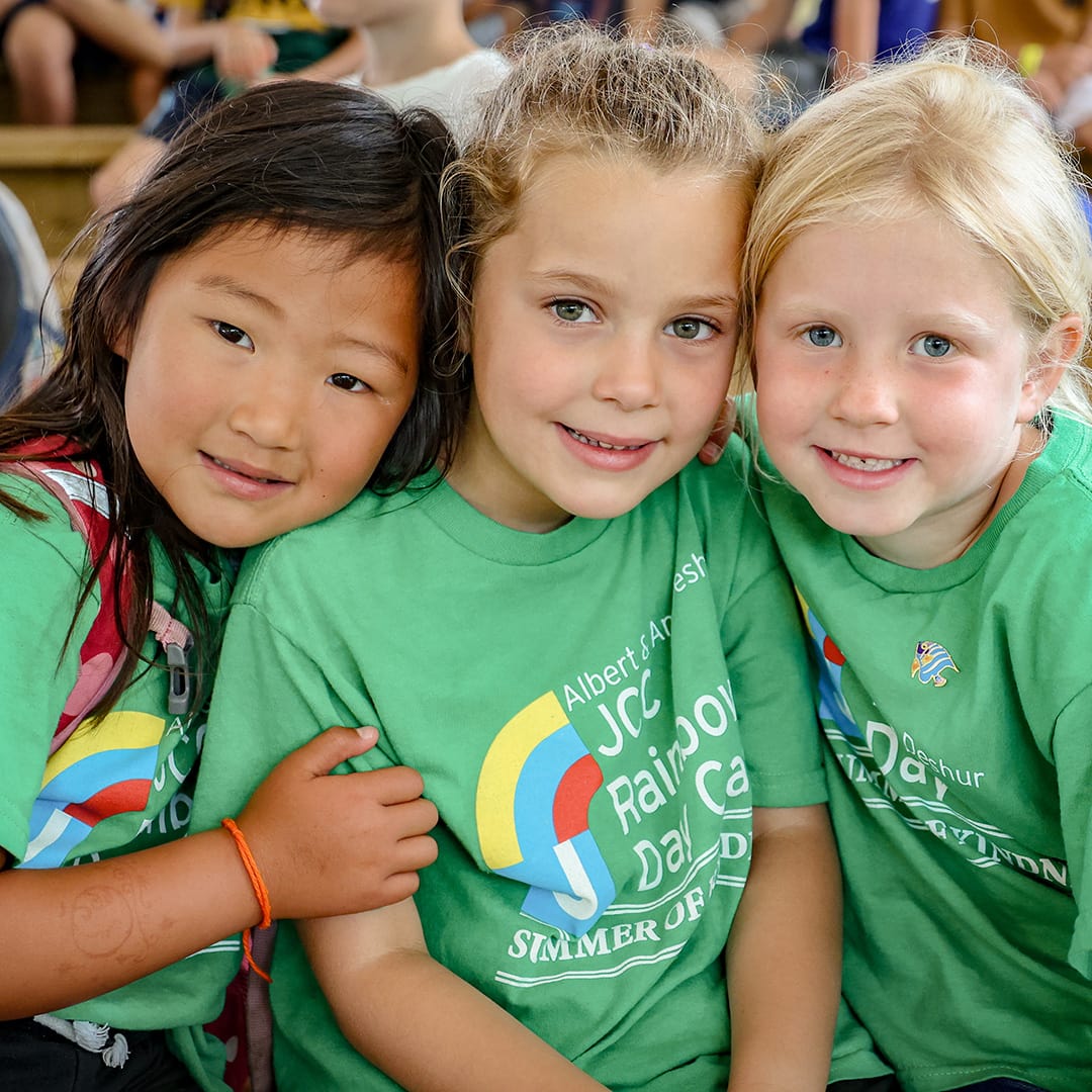 Three young girls wearing green t - shirts.