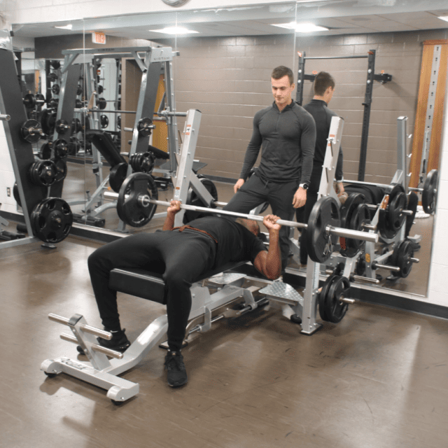 A man doing a bench press in a gym.