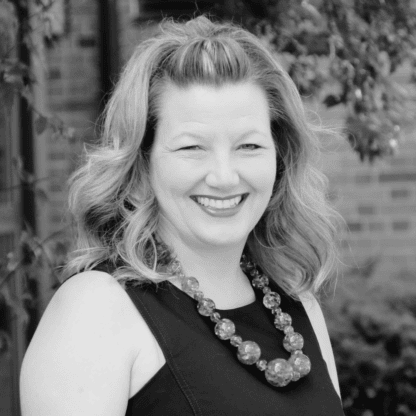 A black and white photo of a smiling woman.