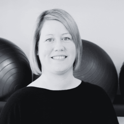 A black and white photo of a woman standing in front of a group of exercise balls.